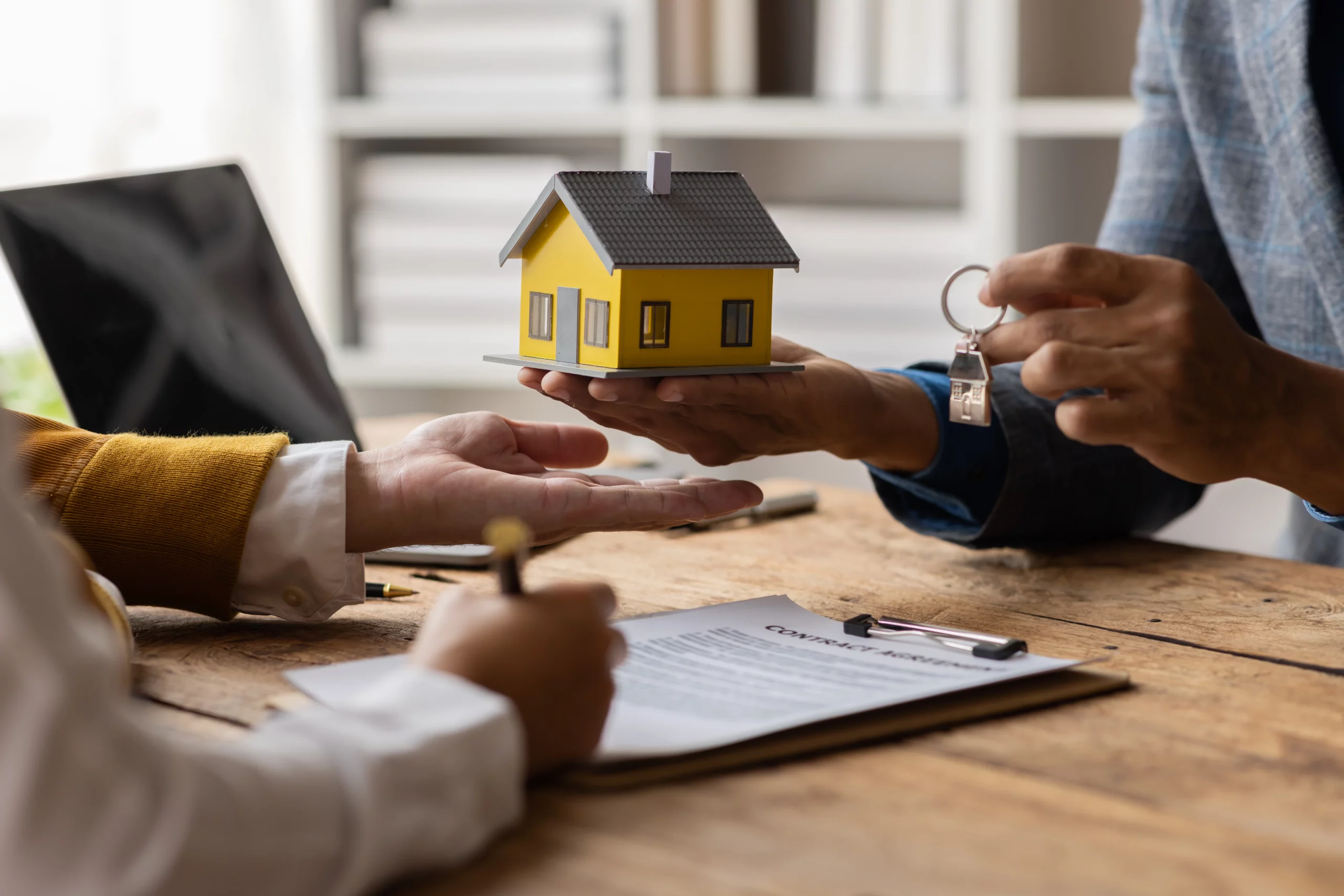 Person completing a home transaction with a house model and key while protecting property through bankruptcy exemptions